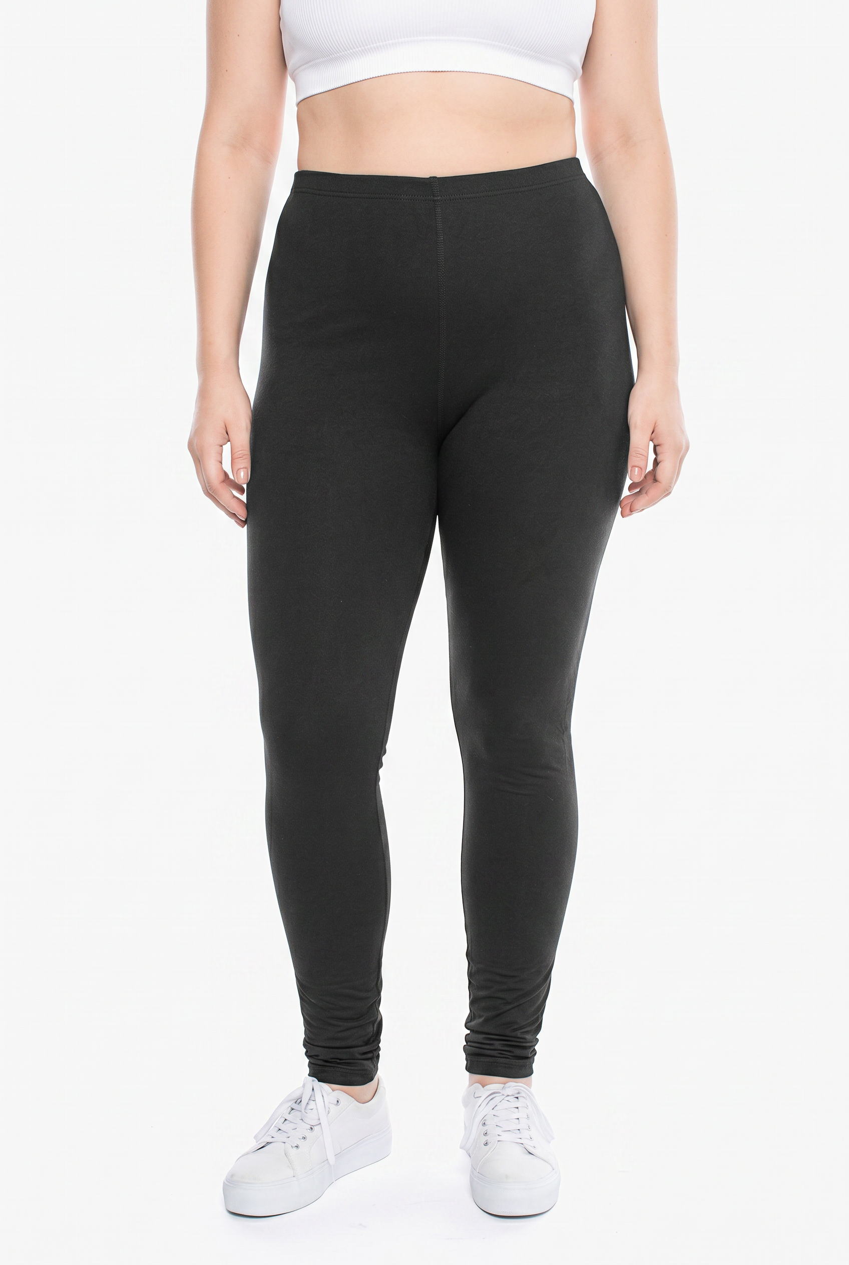 Person wearing black leggings and white sneakers on a white background
